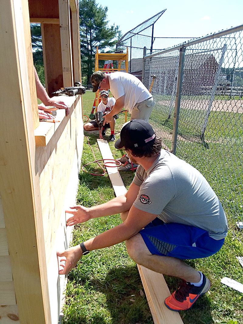 Wayne Highlands Tech Ed teachers and student nail siding to new home dugout at County Farm.